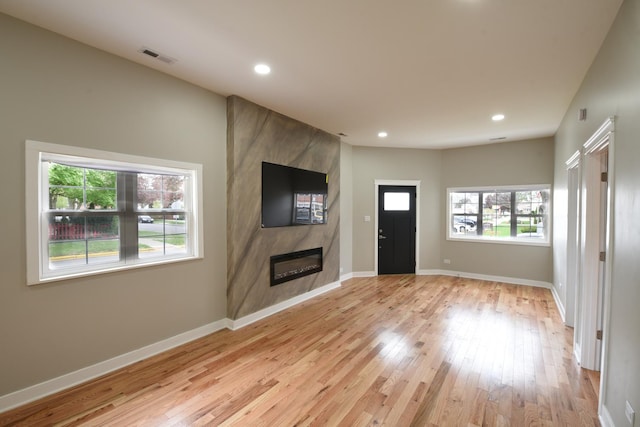 unfurnished living room featuring recessed lighting, visible vents, a large fireplace, and light wood-style floors