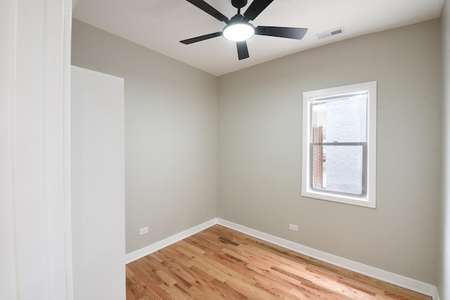 empty room with baseboards, a ceiling fan, light wood-type flooring, and visible vents