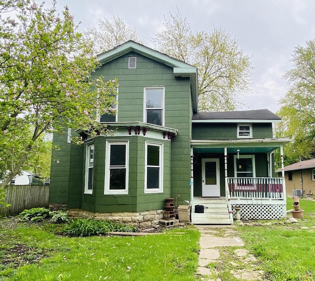 view of front of home featuring a porch, fence, and a front lawn