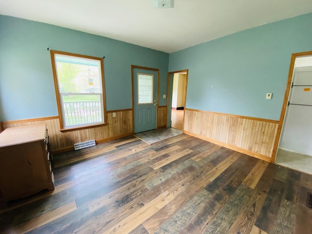 spare room with wood walls, a wainscoted wall, visible vents, and wood finished floors