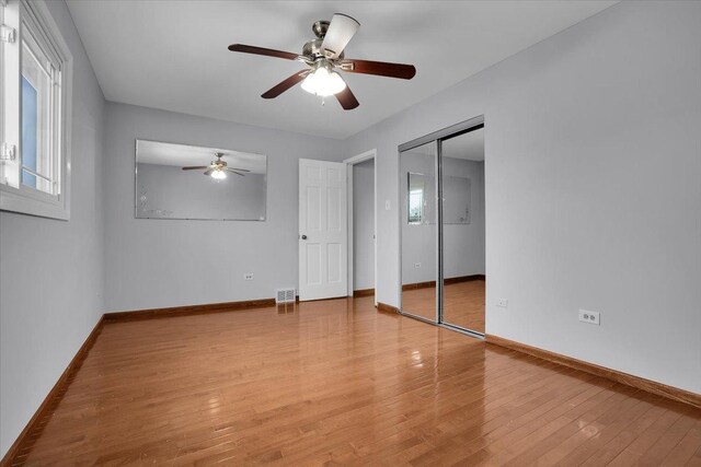 8440 163rd St, Tinley Park, IL 60487 - unfurnished bedroom with a closet, baseboards, ceiling fan, multiple windows, and light wood-type flooring
