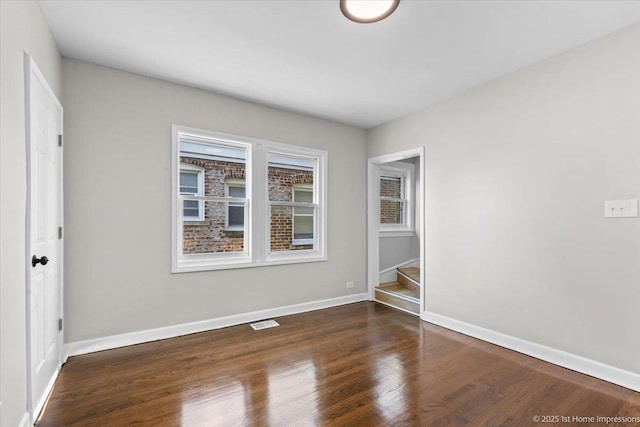 empty room with visible vents, stairs, baseboards, and wood finished floors
