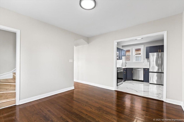 unfurnished living room featuring baseboards, stairs, and light wood-style flooring