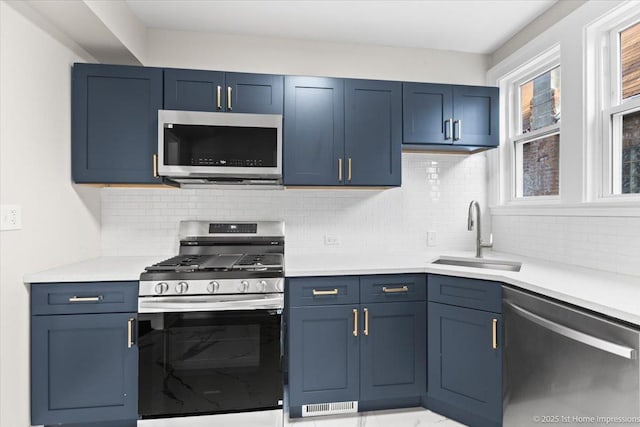 kitchen with backsplash, blue cabinets, a sink, light countertops, and stainless steel appliances