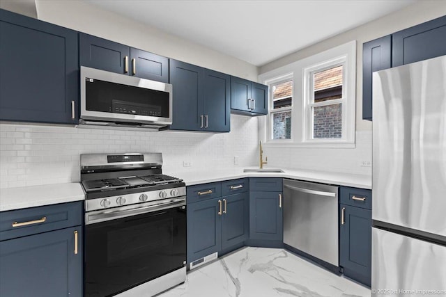 kitchen featuring appliances with stainless steel finishes, a sink, light countertops, blue cabinetry, and marble finish floor