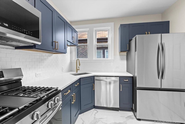 kitchen featuring marble finish floor, light countertops, blue cabinets, a sink, and appliances with stainless steel finishes