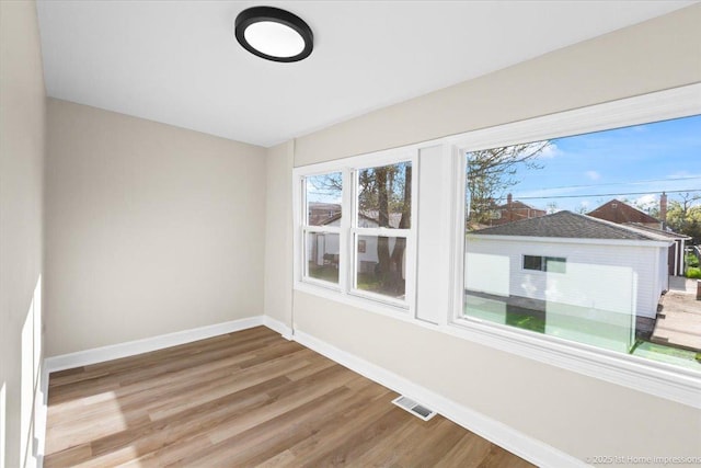 spare room with baseboards, wood finished floors, and visible vents