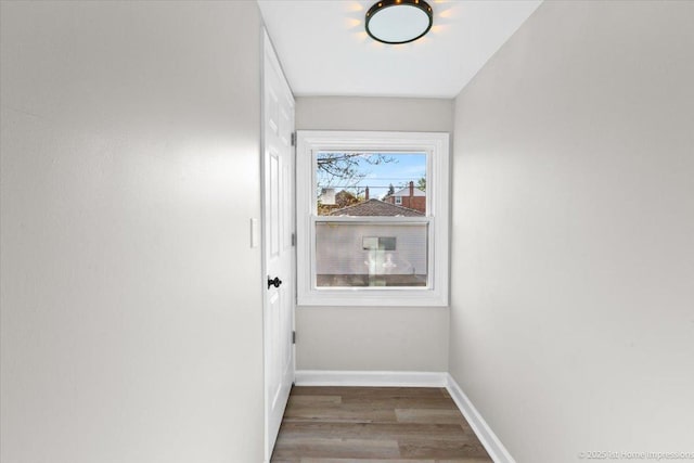 doorway featuring baseboards and wood finished floors