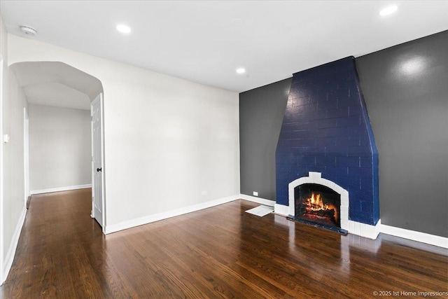 unfurnished living room with recessed lighting, baseboards, wood finished floors, and a fireplace