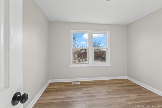 unfurnished room featuring baseboards, visible vents, and light wood-style flooring
