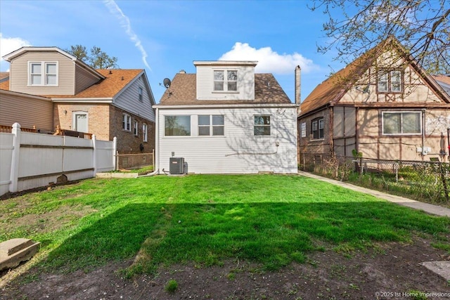 back of house featuring a lawn, central AC, and a fenced backyard
