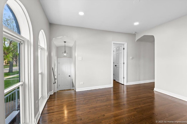 unfurnished room with recessed lighting, arched walkways, baseboards, and wood finished floors