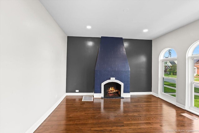 unfurnished living room featuring baseboards, a brick fireplace, recessed lighting, and wood finished floors