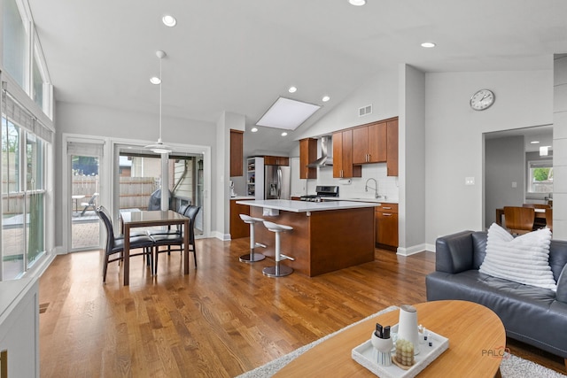 living area featuring a skylight, dark wood finished floors, high vaulted ceiling, baseboards, and recessed lighting