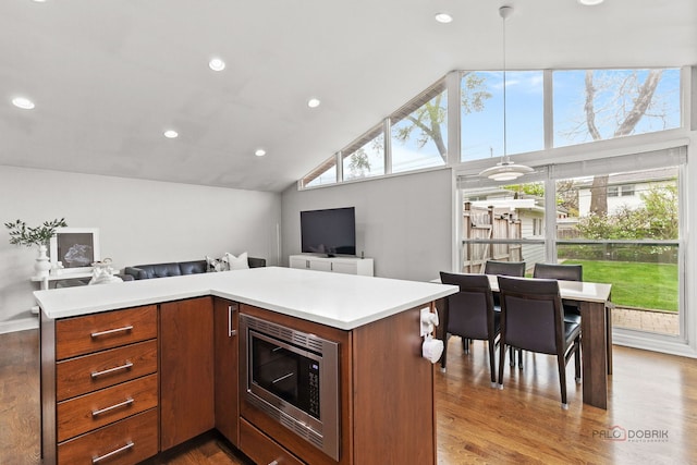 kitchen with light countertops, recessed lighting, stainless steel microwave, open floor plan, and wood finished floors
