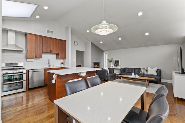 dining space with visible vents, wood finished floors, vaulted ceiling, and a fireplace