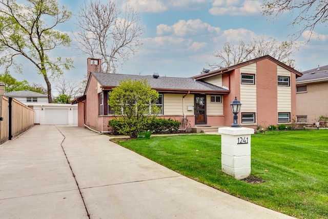split level home with a chimney, a front yard, an outbuilding, a detached garage, and brick siding