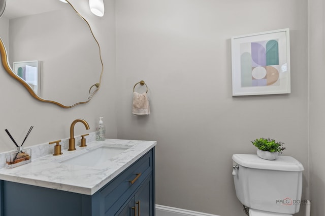 half bathroom featuring vanity, baseboards, and toilet