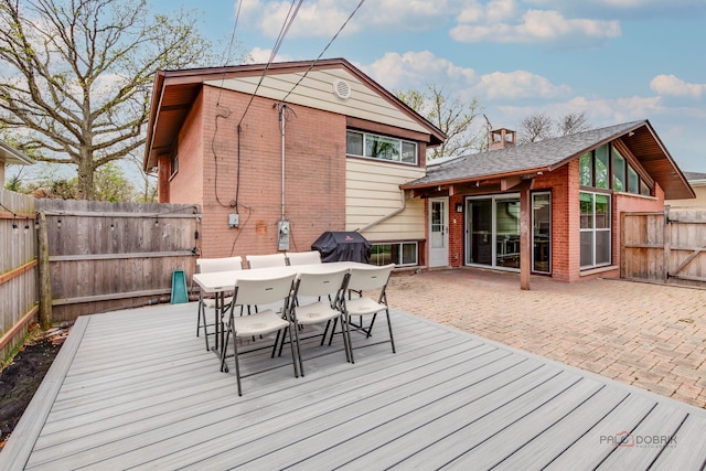 wooden terrace with area for grilling, outdoor dining area, a fenced backyard, and a patio area
