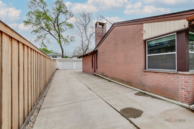 view of side of property with a garage, an outbuilding, a chimney, and brick siding