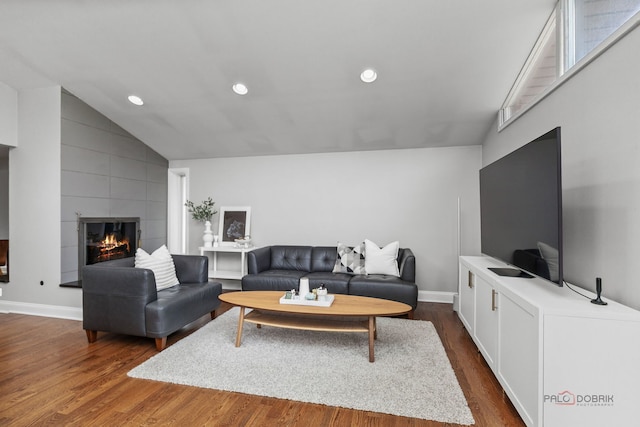 living room featuring dark wood-style flooring, a tiled fireplace, baseboards, lofted ceiling, and recessed lighting