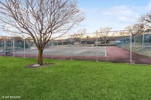 view of sport court with fence and a lawn