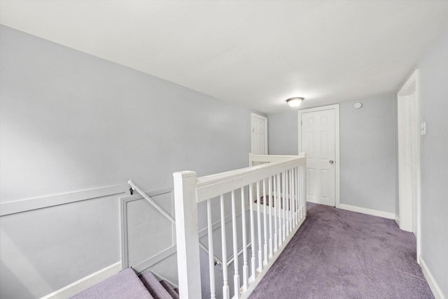 hall featuring baseboards, carpet flooring, and an upstairs landing