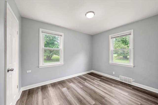 spare room featuring visible vents, baseboards, and wood finished floors