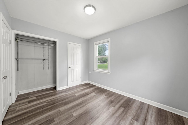 unfurnished bedroom with baseboards, wood finished floors, and a closet