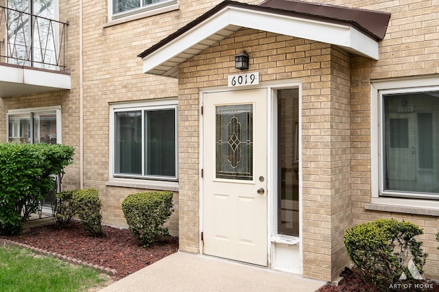 view of exterior entry featuring brick siding