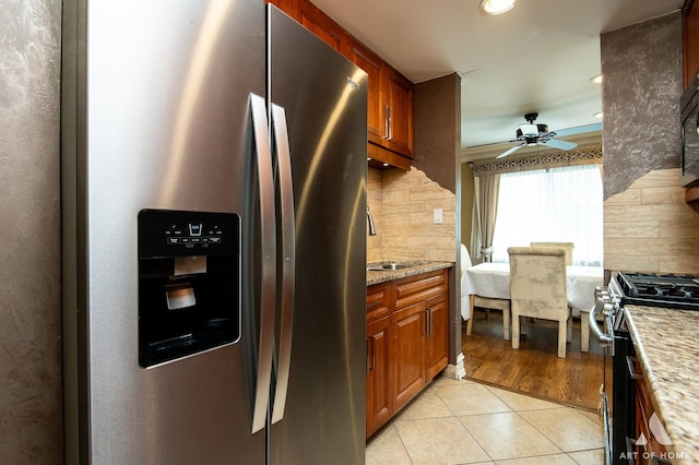 kitchen with a sink, tasteful backsplash, a ceiling fan, appliances with stainless steel finishes, and light tile patterned floors