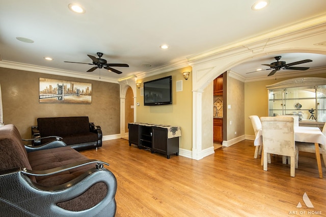 living room featuring crown molding, arched walkways, a ceiling fan, and light wood-type flooring