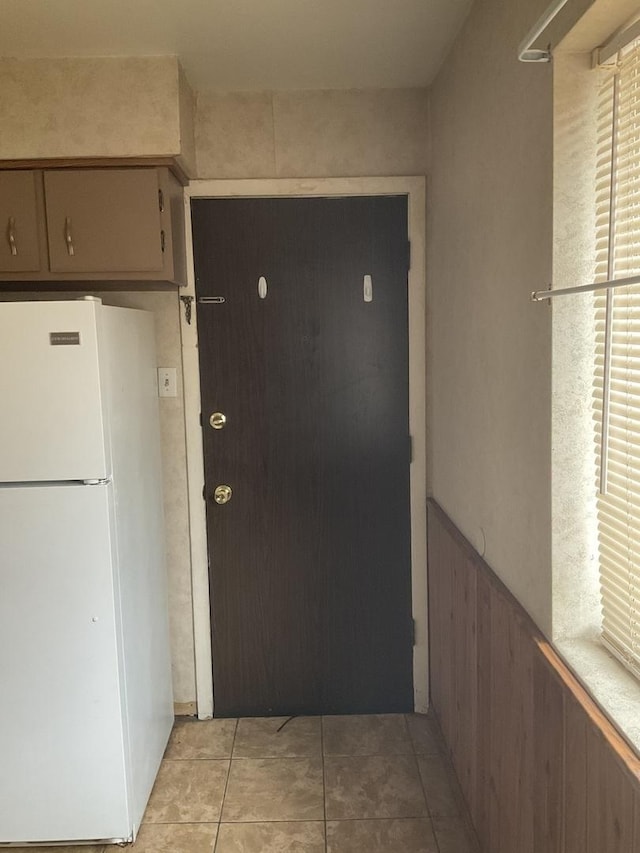 3010 Bernice Rd Unit 104, Lansing, IL 60438 - kitchen with freestanding refrigerator, a wainscoted wall, light tile patterned floors, and wooden walls