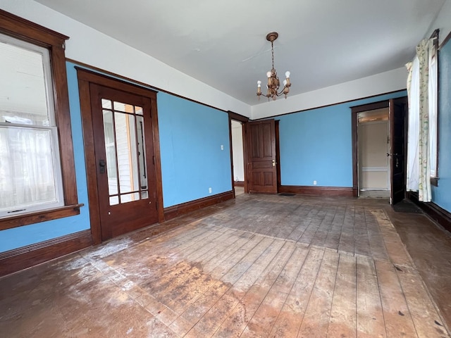 unfurnished room with baseboards and a chandelier