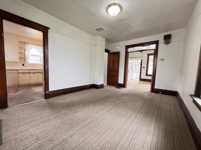 empty room with visible vents, carpet flooring, baseboards, and a healthy amount of sunlight