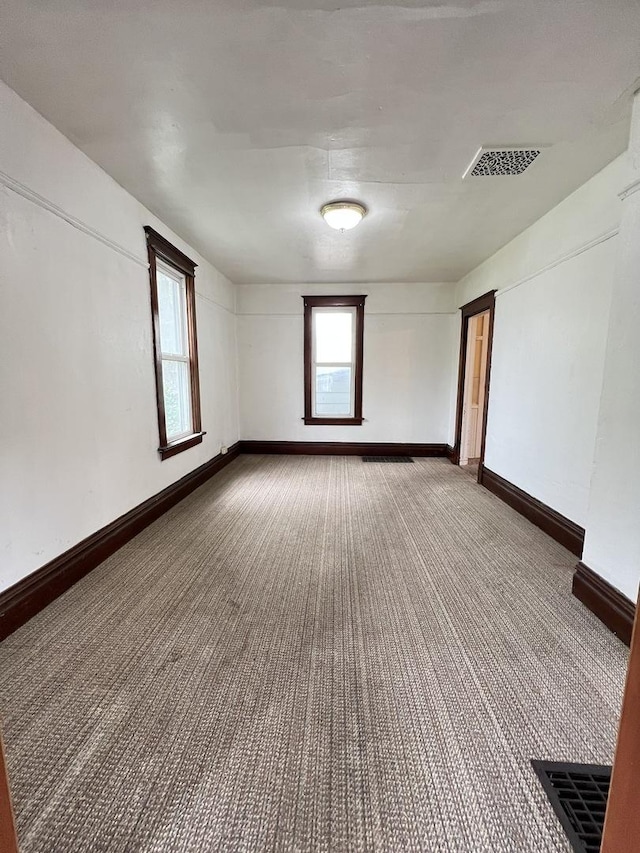 carpeted empty room featuring baseboards and visible vents