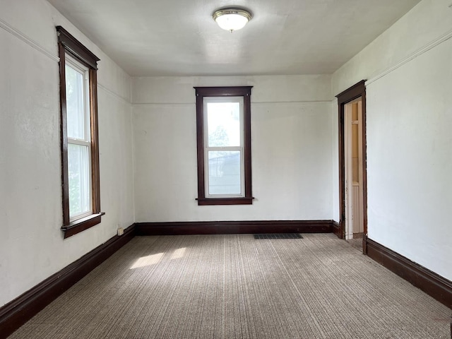 carpeted spare room with visible vents and baseboards