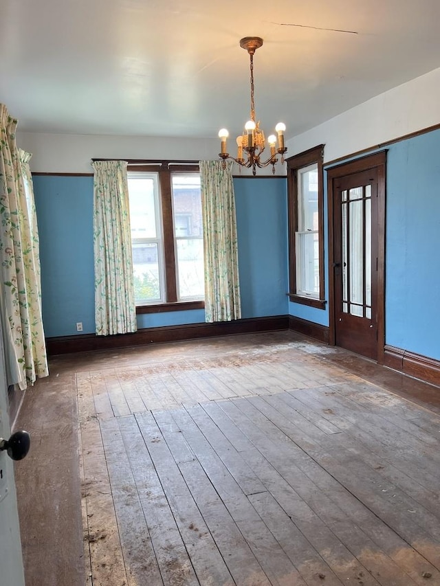 unfurnished dining area with baseboards, a chandelier, and a healthy amount of sunlight