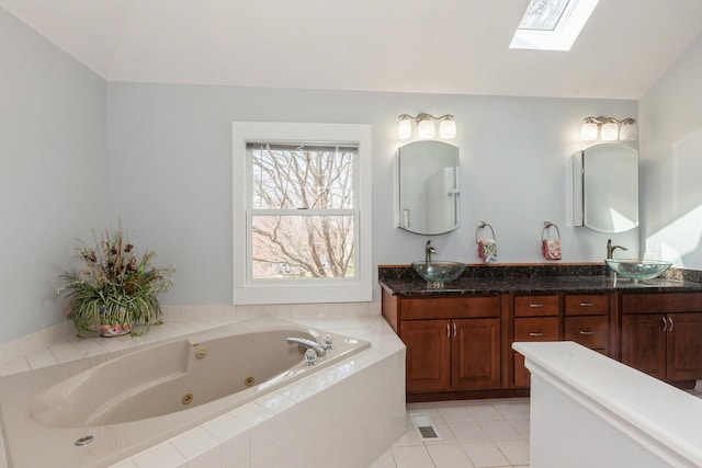 full bath featuring double vanity, tile patterned floors, a sink, and a jetted tub