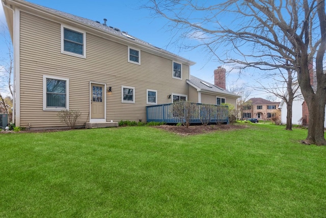 back of property with a lawn, a wooden deck, and a chimney