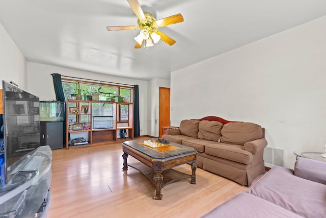 living room featuring a ceiling fan, visible vents, and light wood-style flooring
