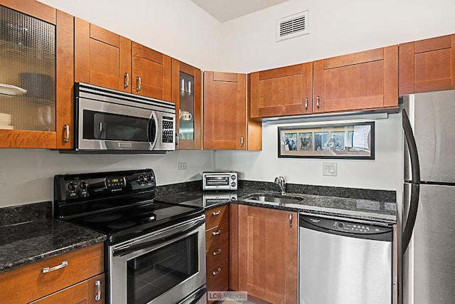 175 E Delaware Pl Unit 5019, Chicago, IL 60611 - kitchen featuring stainless steel appliances, a sink, brown cabinetry, dark stone counters, and glass insert cabinets