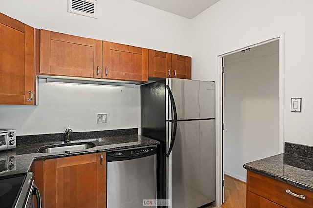 175 E Delaware Pl Unit 5019, Chicago, IL 60611 - kitchen with appliances with stainless steel finishes, a sink, dark stone counters, brown cabinetry, and light wood-style flooring