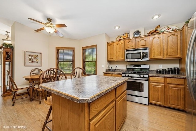 kitchen with stainless steel appliances, a center island, light wood finished floors, ceiling fan, and recessed lighting