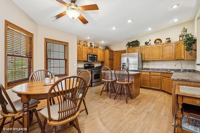 kitchen featuring appliances with stainless steel finishes, a kitchen island, light wood finished floors, brown cabinets, and recessed lighting
