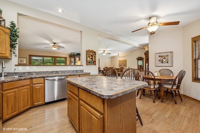 kitchen with stainless steel dishwasher, a sink, brown cabinetry, a center island, and ceiling fan