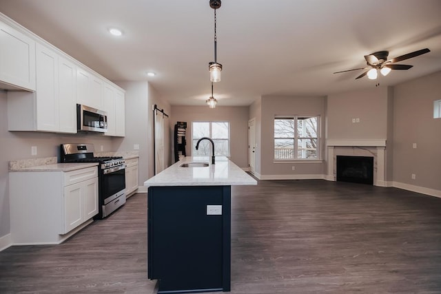 kitchen with a sink, appliances with stainless steel finishes, baseboards, and ceiling fan