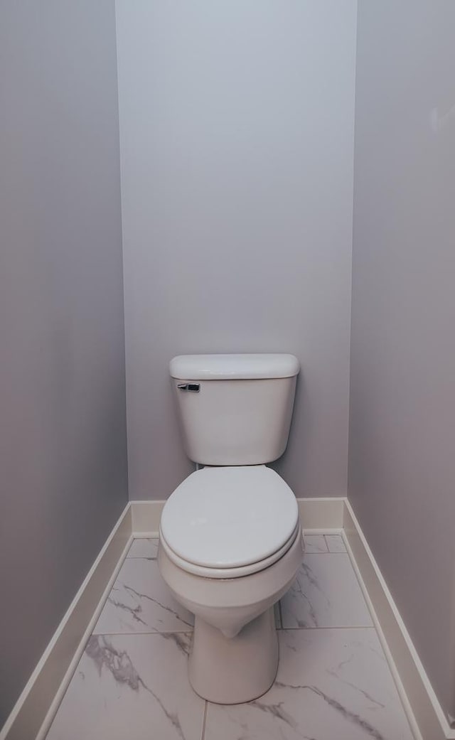 bathroom featuring baseboards, toilet, and marble finish floor