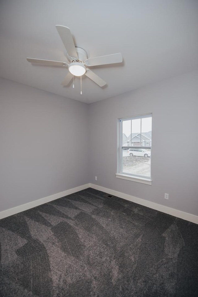 empty room featuring baseboards, a ceiling fan, and dark colored carpet