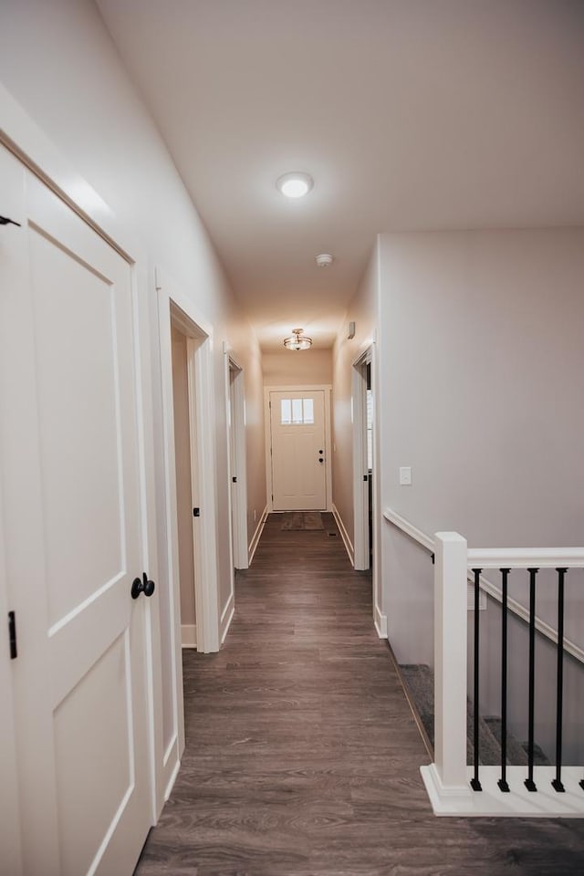 hall featuring dark wood-type flooring and baseboards